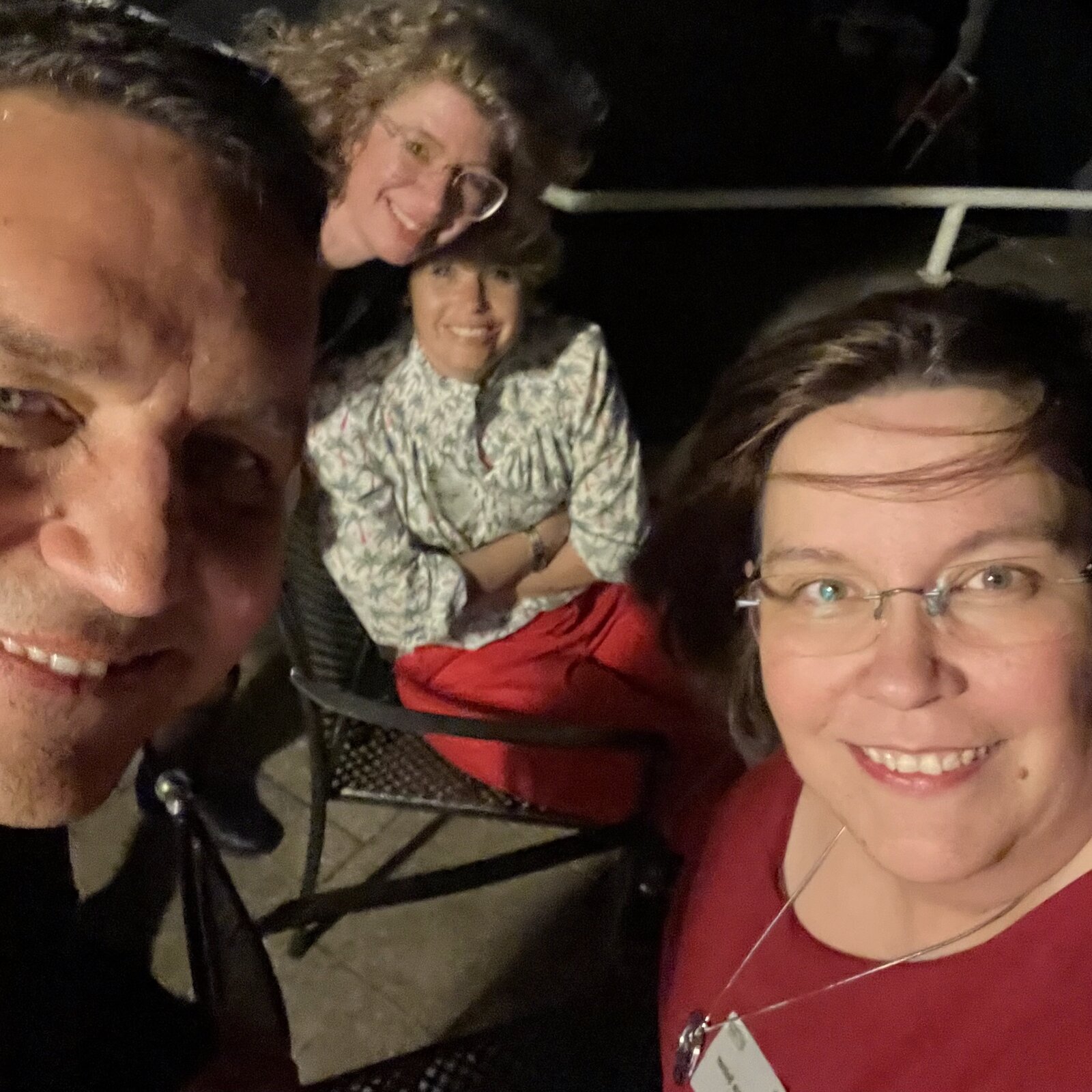 Selfie von vier Personen abends im Dunkeln auf einer Terrasse, zwei davon sitzen im Hintergrund